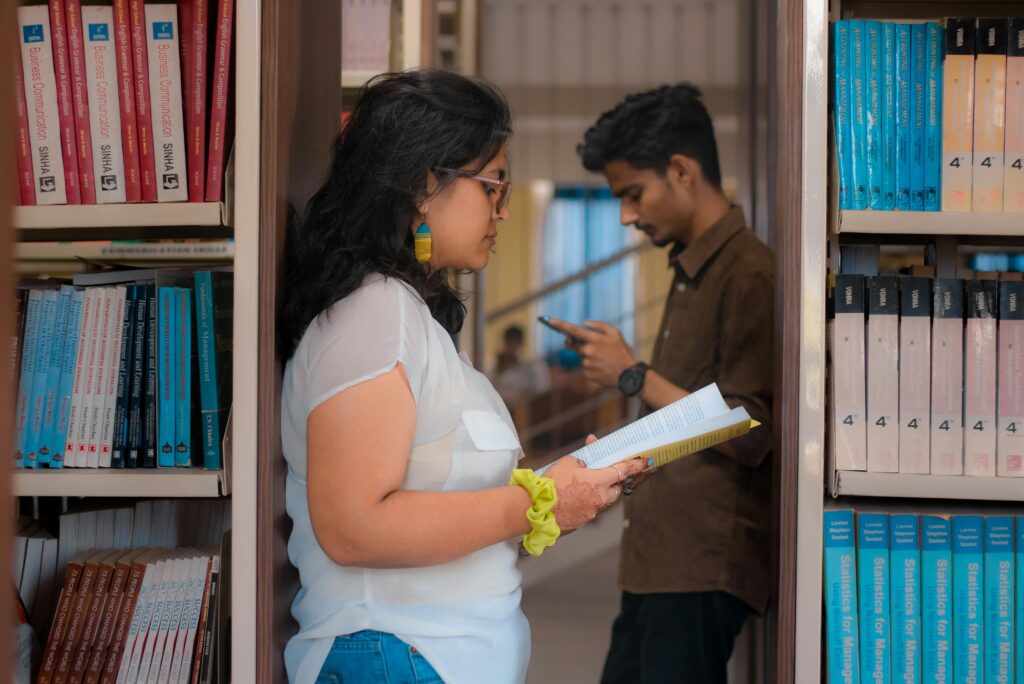 Two students studying among bookshelves in a New Delhi library.