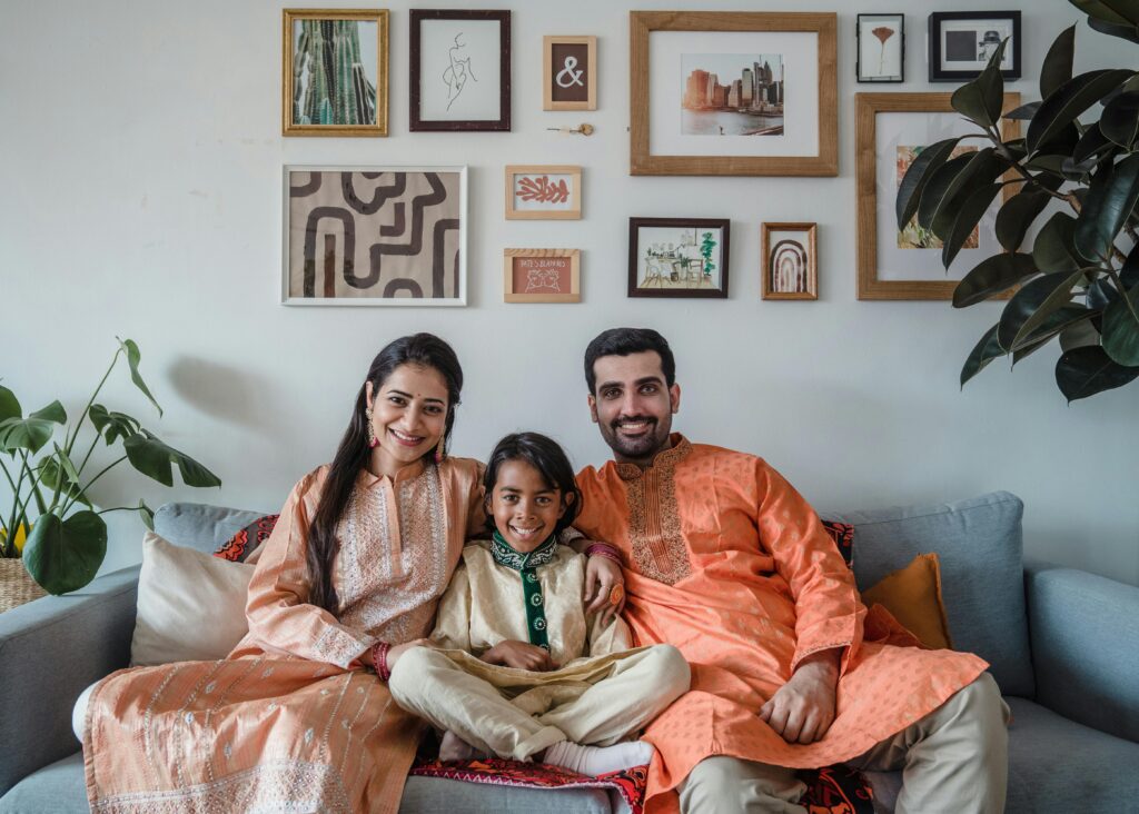 Smiling family of three in traditional clothing sitting on sofa indoors, embodying togetherness.